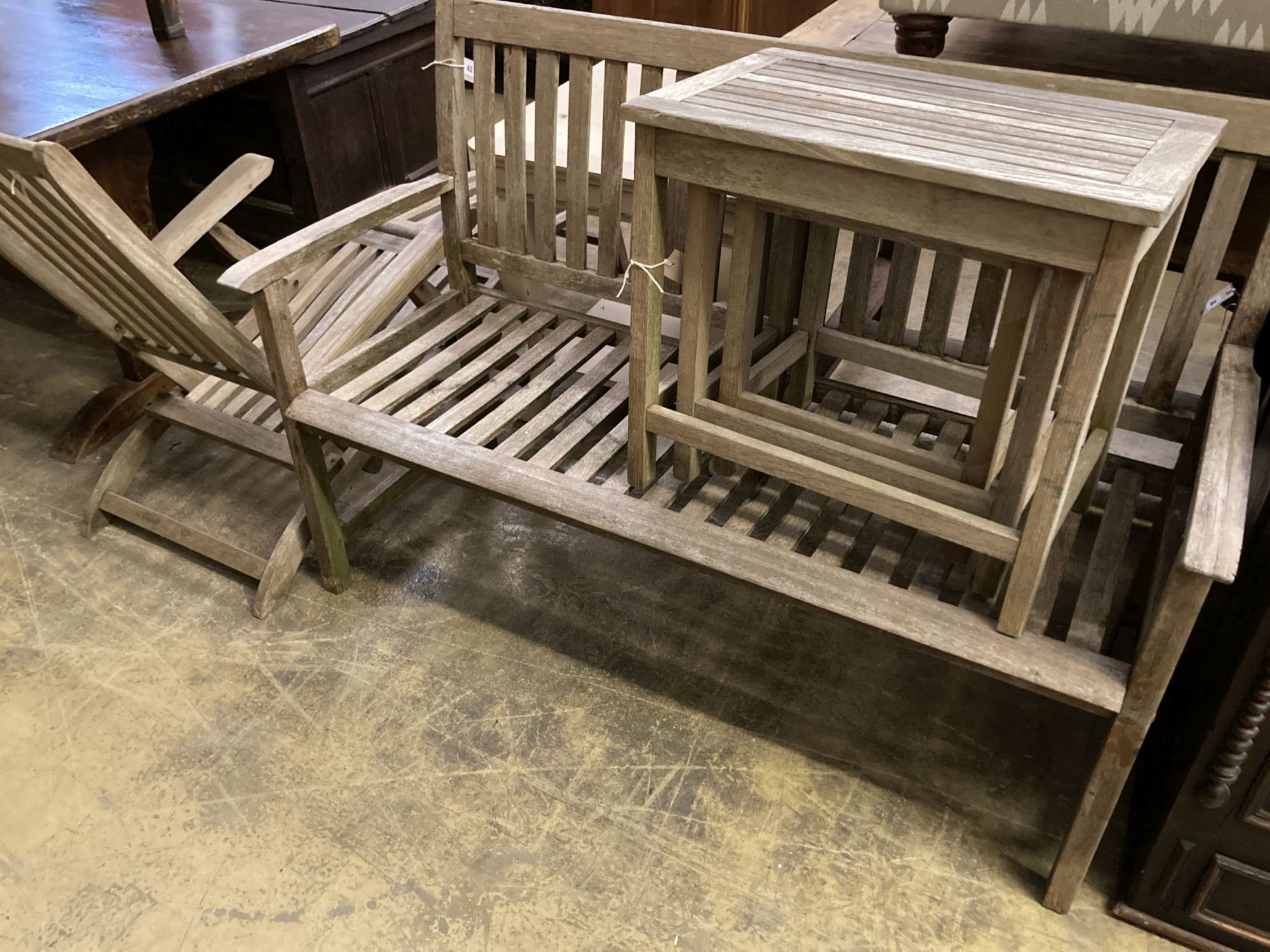 A weathered teak garden bench, length 129cm together with a teak steamer chair and nest of three teak rectangular garden tables